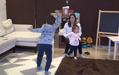 Children dancing around the living room with mother